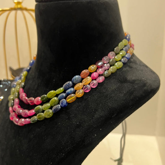 A multi-color beaded necklace displayed on a mannequin, featuring multiple strands and an adjustable dori.