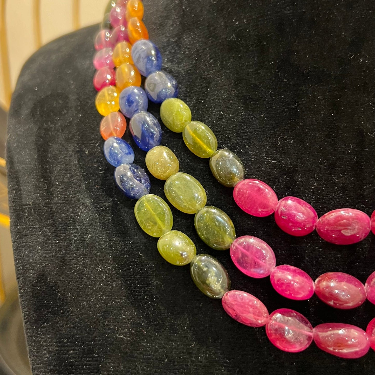 A multi-color beaded necklace displayed on a mannequin, featuring multiple strands and an adjustable dori.