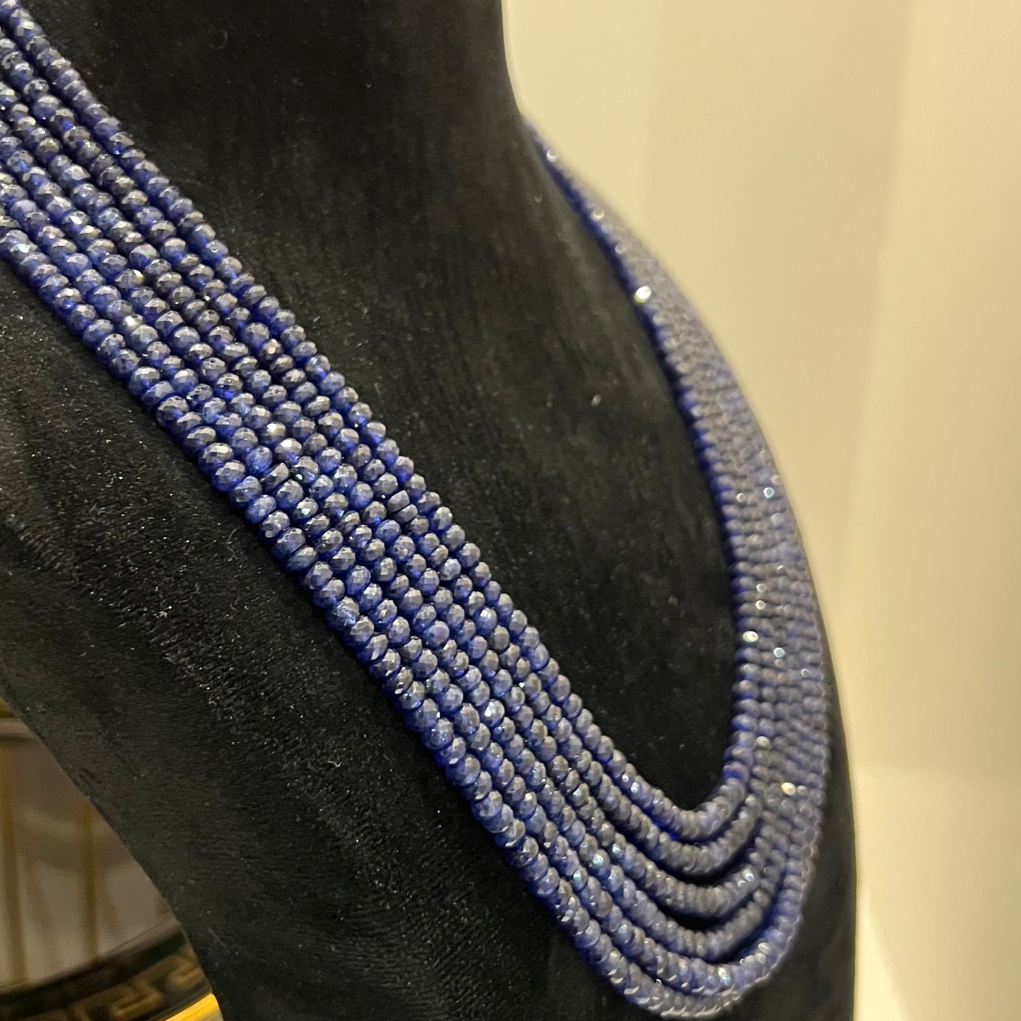 A multi-strand 6 layer blue sapphire beads necklace displayed on a black mannequin bust.