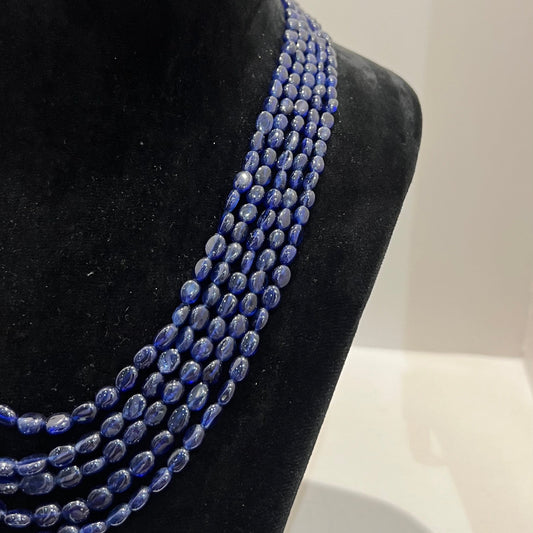 A multi-strand 5 layer blue sapphire beads necklace displayed on a mannequinnecklace stand.