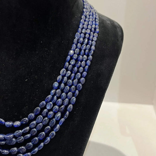 A multi-strand 5 layer blue sapphire beads necklace displayed on a mannequinnecklace stand.