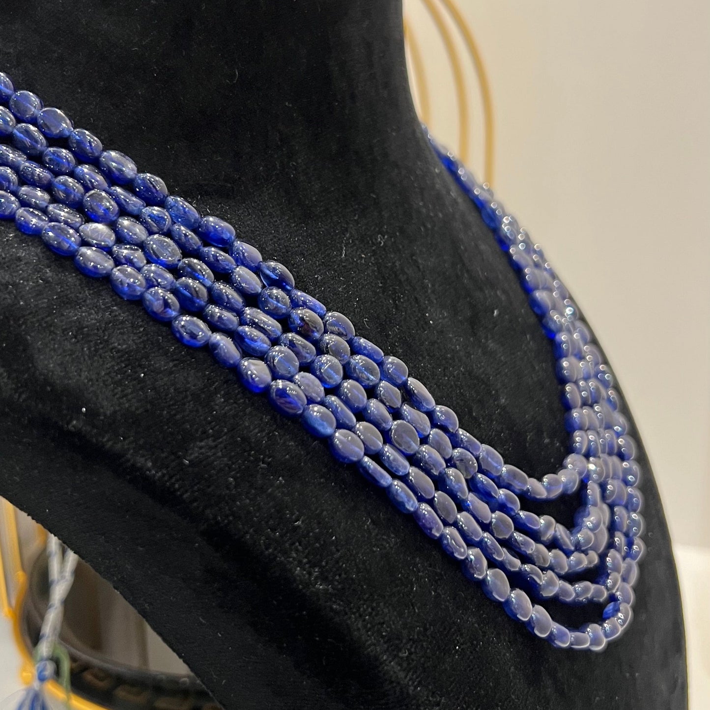 A multi-strand 5 layer blue sapphire beads necklace displayed on a mannequinnecklace stand.