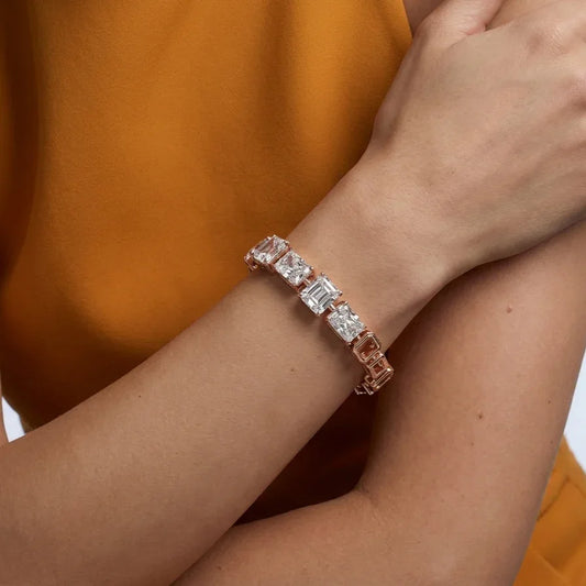 Rose gold bracelet with real diamonds on a wrist against an orange background