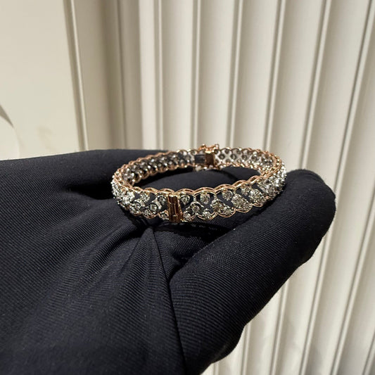 A luxurious diamond gold tennis bracelet with openable sections, featuring gold color and adorned with genuine diamonds, displayed by a hand.