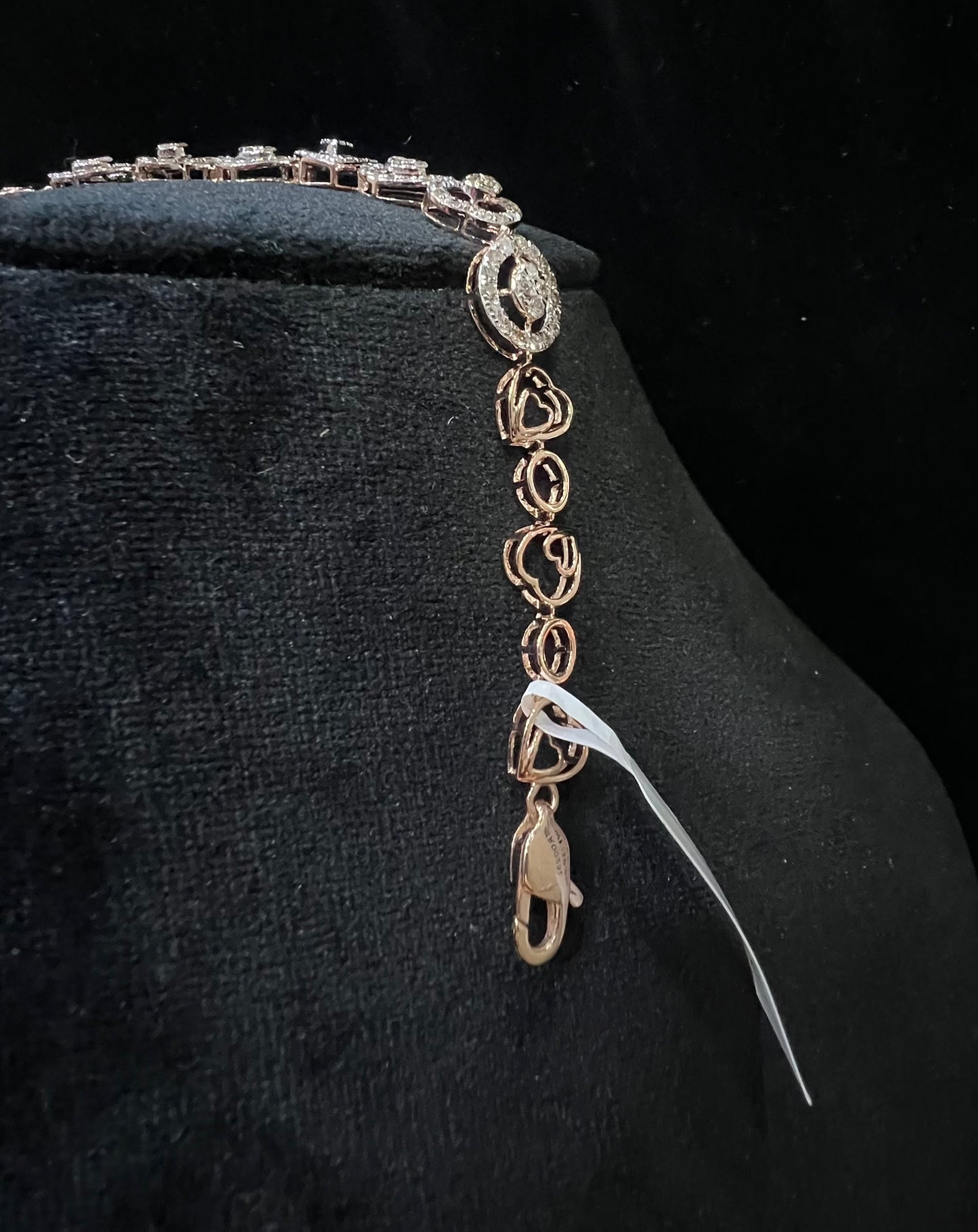 A gold diamond bracelet with oval heart shapes, displayed on a black mannequin.