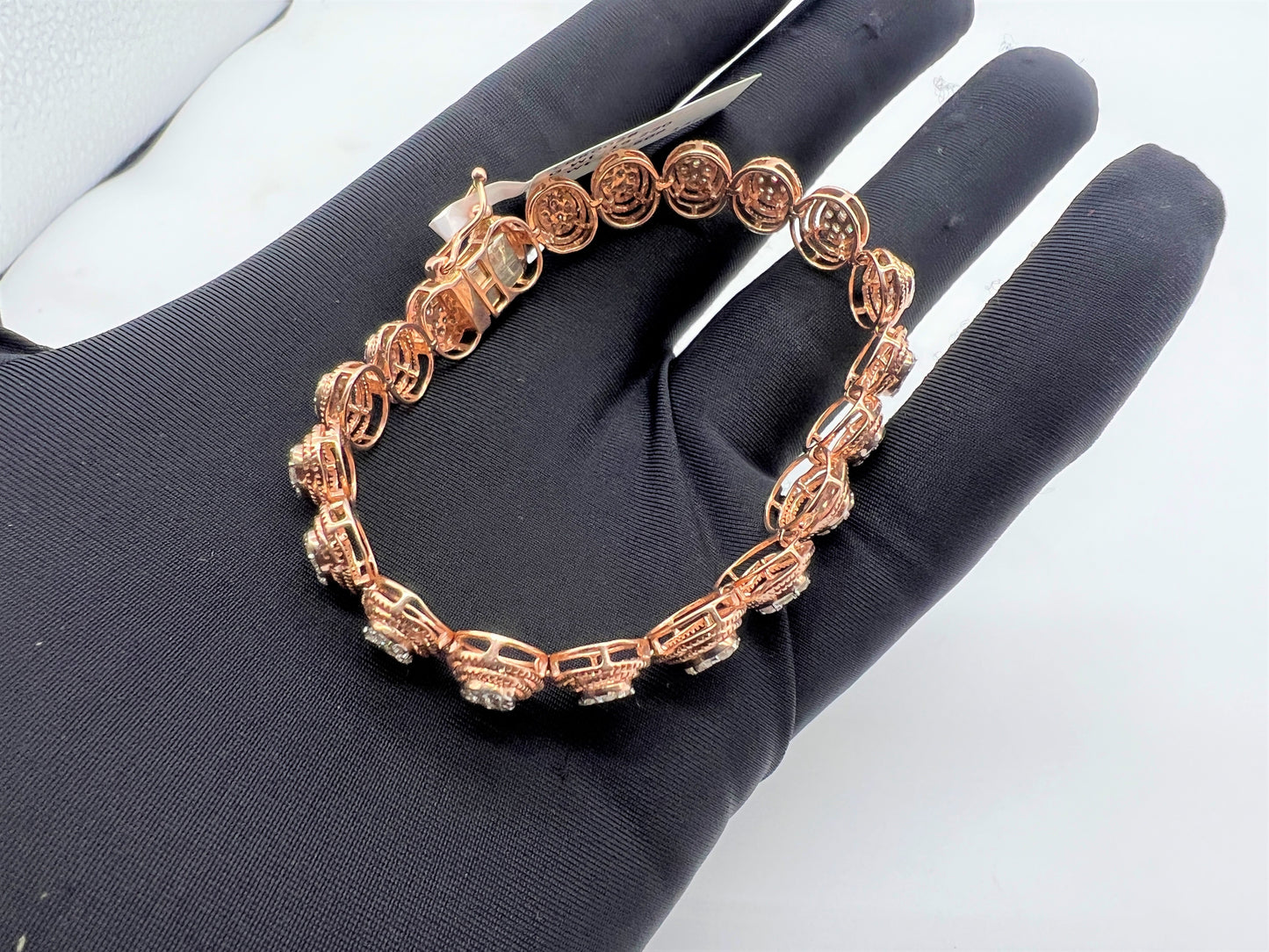 A gold diamond bracelet with multiple rows of inset stones, displayed on a mannequin hand.