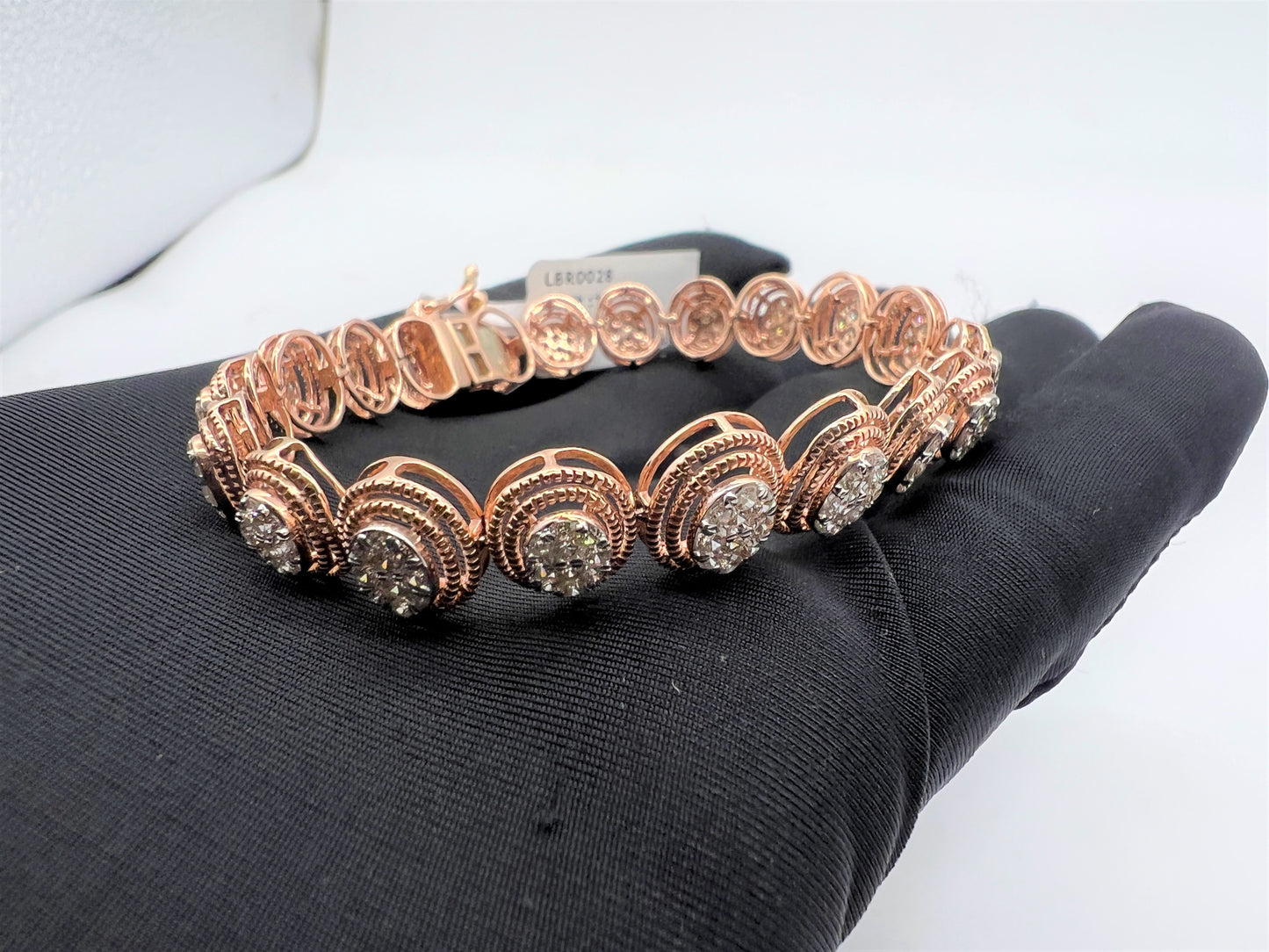 A gold diamond bracelet with multiple rows of inset stones, displayed on a mannequin hand.