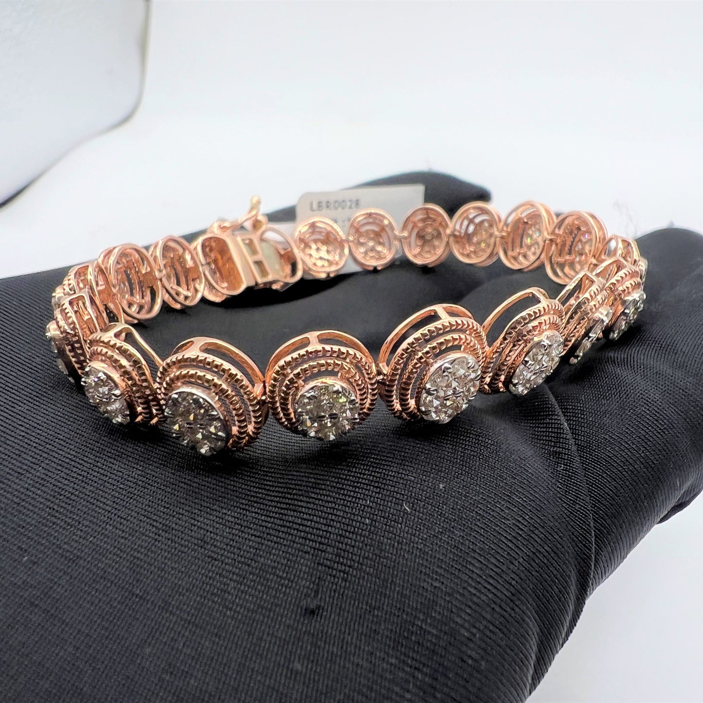 A gold diamond bracelet with multiple rows of inset stones, displayed on a mannequin hand.