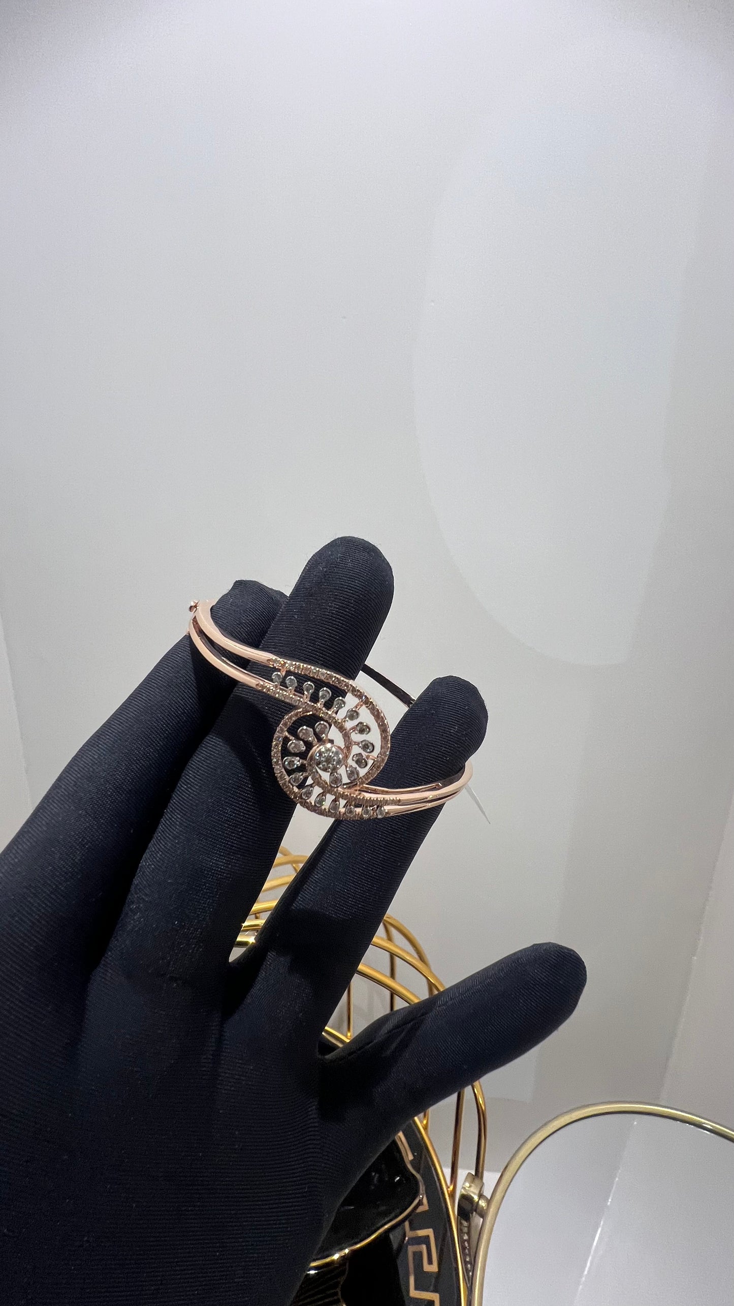 A luxurious gold diamond bracelet with a openable design, featuring a central oval-shaped diamond surrounded by smaller diamonds set in a brilliant cut, displayed on a mannequin hand.