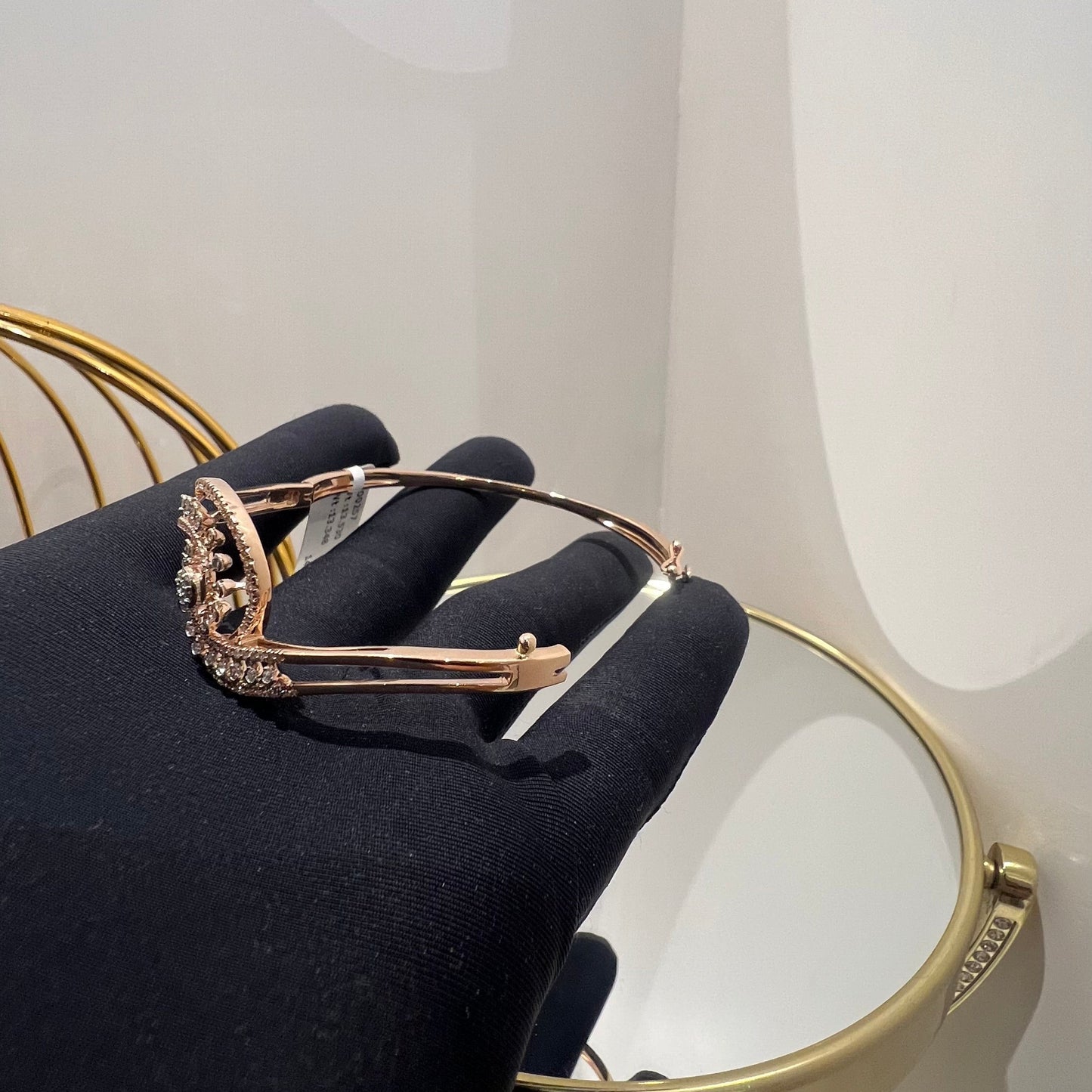 A luxurious gold diamond bracelet with a openable design, featuring a central oval-shaped diamond surrounded by smaller diamonds set in a brilliant cut, displayed on a hand.