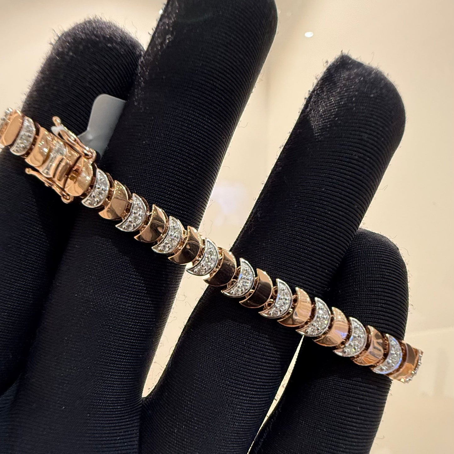 A gold diamond tennis bracelet with white diamonds, held on a mannequin arm.