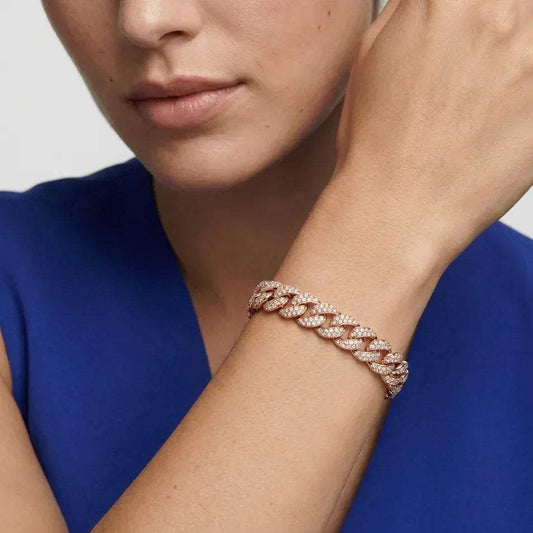 A woman in blue color dress showing a cuban link real diamond bracelet worn in her hand.