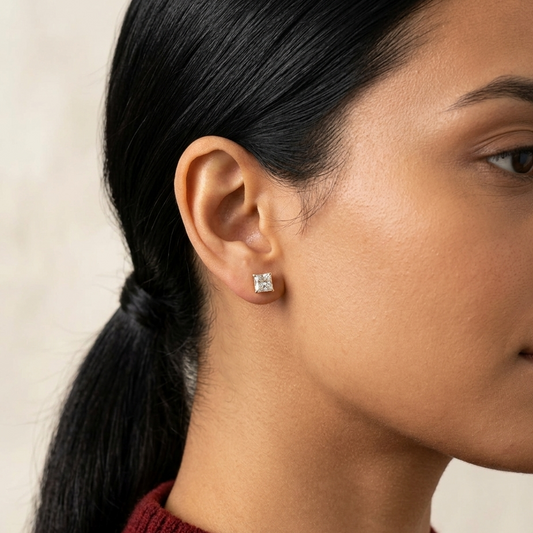 Close-up of a person wearing a diamond stud earring with a neutral background