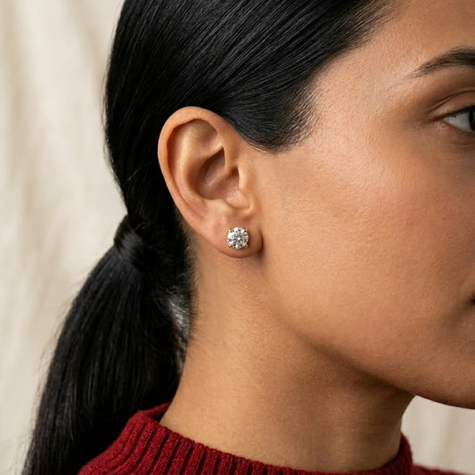 Close-up of a woman wearing a diamond stud earring with a neutral background