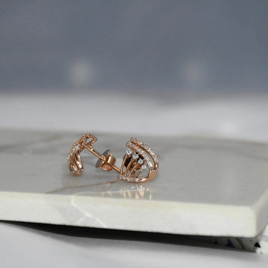 Rose gold earrings with diamonds on a marble surface