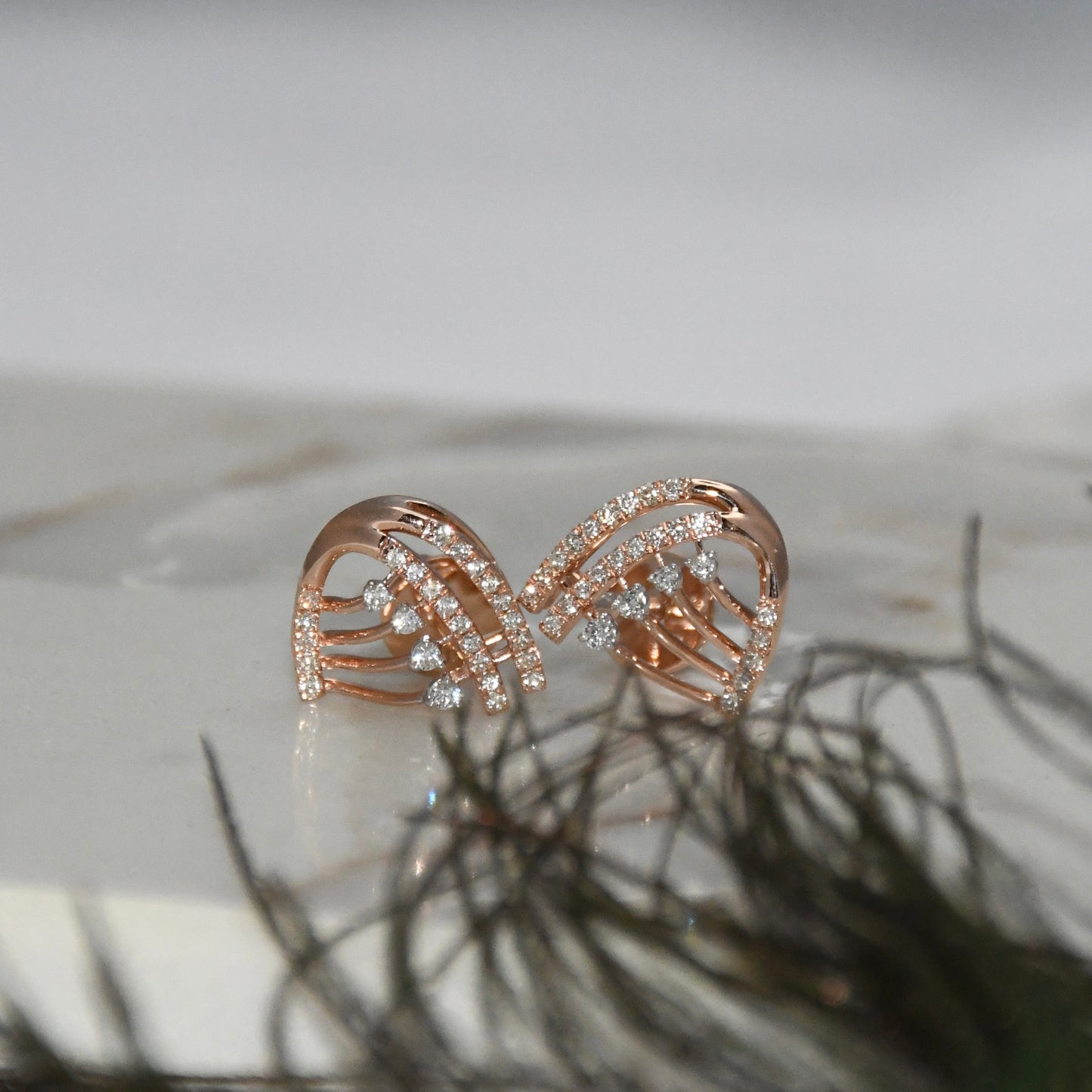 Rose gold bow-shaped earrings with clear diamonds on a light background