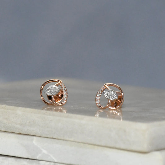 Rose gold earrings with diamond accents on a marble surface with a gray background