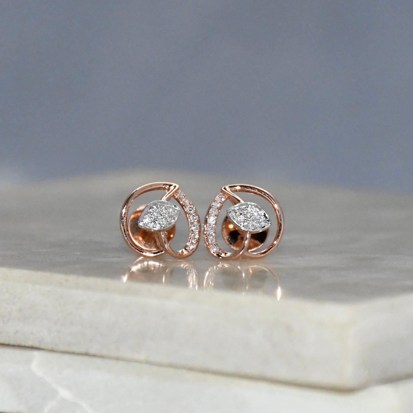 Rose gold earrings with diamonds on a marble surface