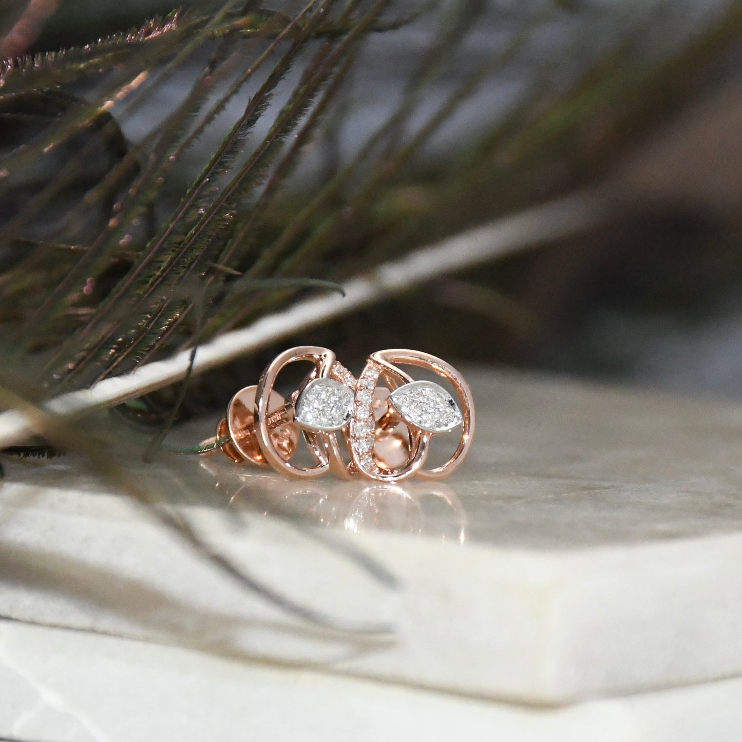 Rose gold earrings with diamond accents on a natural background