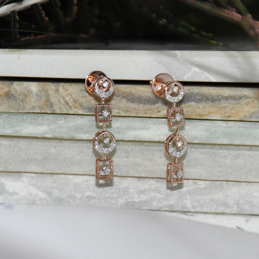 Rose gold earrings with diamond accents on a marble surface