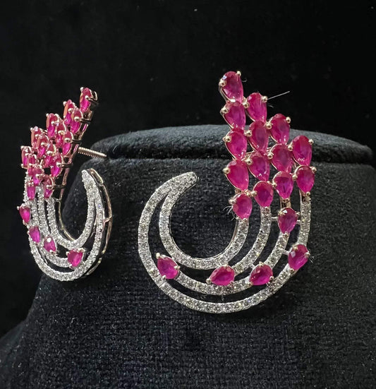 Pair of color stone and diamond swirl earrings with multiple pear-shaped color stones and round diamonds set in a circular design on a black display stand.