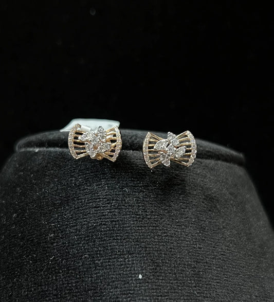 A pair of gold diamond earrings with a round cut design on a mannequin stand.