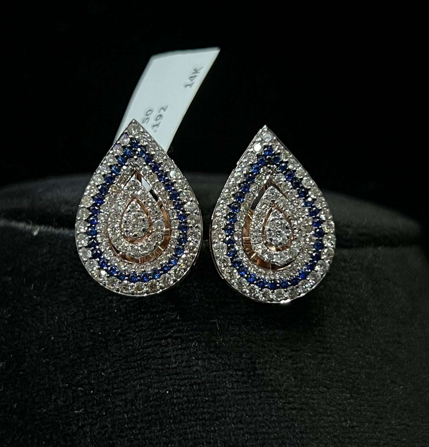 A pair of gold diamond earrings with a geometric pattern, displayed on a mannequin bust.