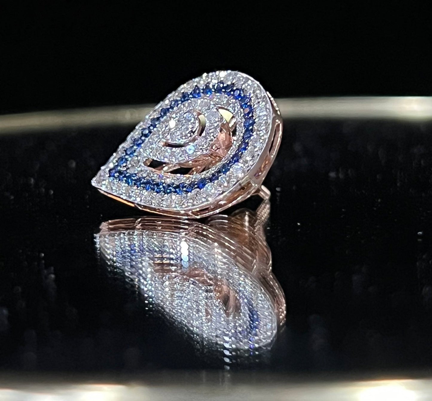A pair of gold diamond earrings with a geometric pattern, displayed on a reflective surface.