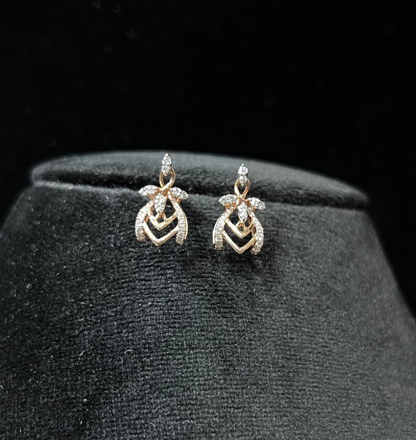 A pair of diamond earrings with a rose gold or gold color finish, featuring a V-shaped design with diamond embellishments.