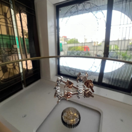 A pair of gold diamond earrings held on a reflective surface, with a clear and bright design.