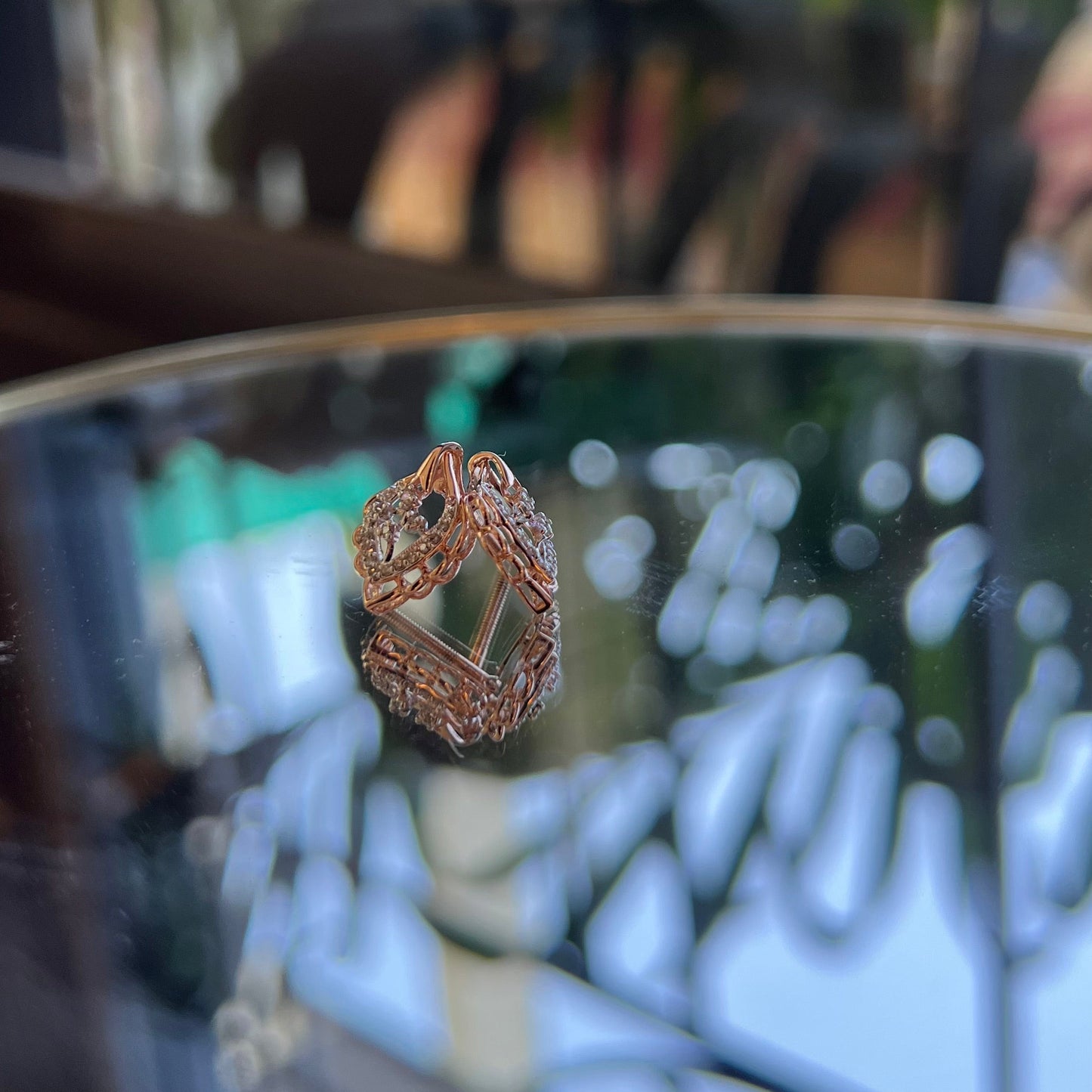 A pair of diamond stud earrings displayed on a reflective surface.