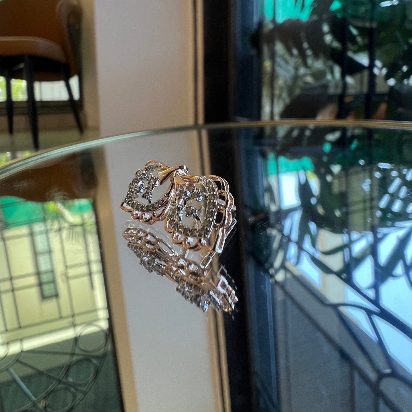 A pair of diamond stud earrings displayed on a reflective surface.