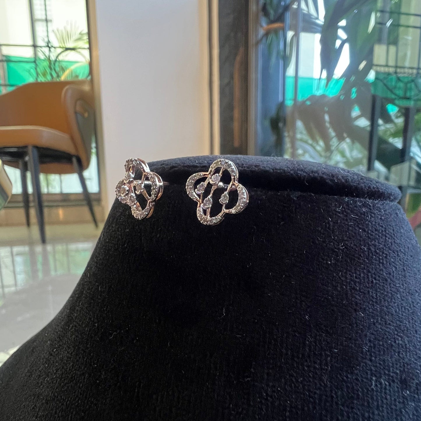 Pair of clover bloom diamond stud earrings in gold, designed with open quatrefoil petals and diamond accents.