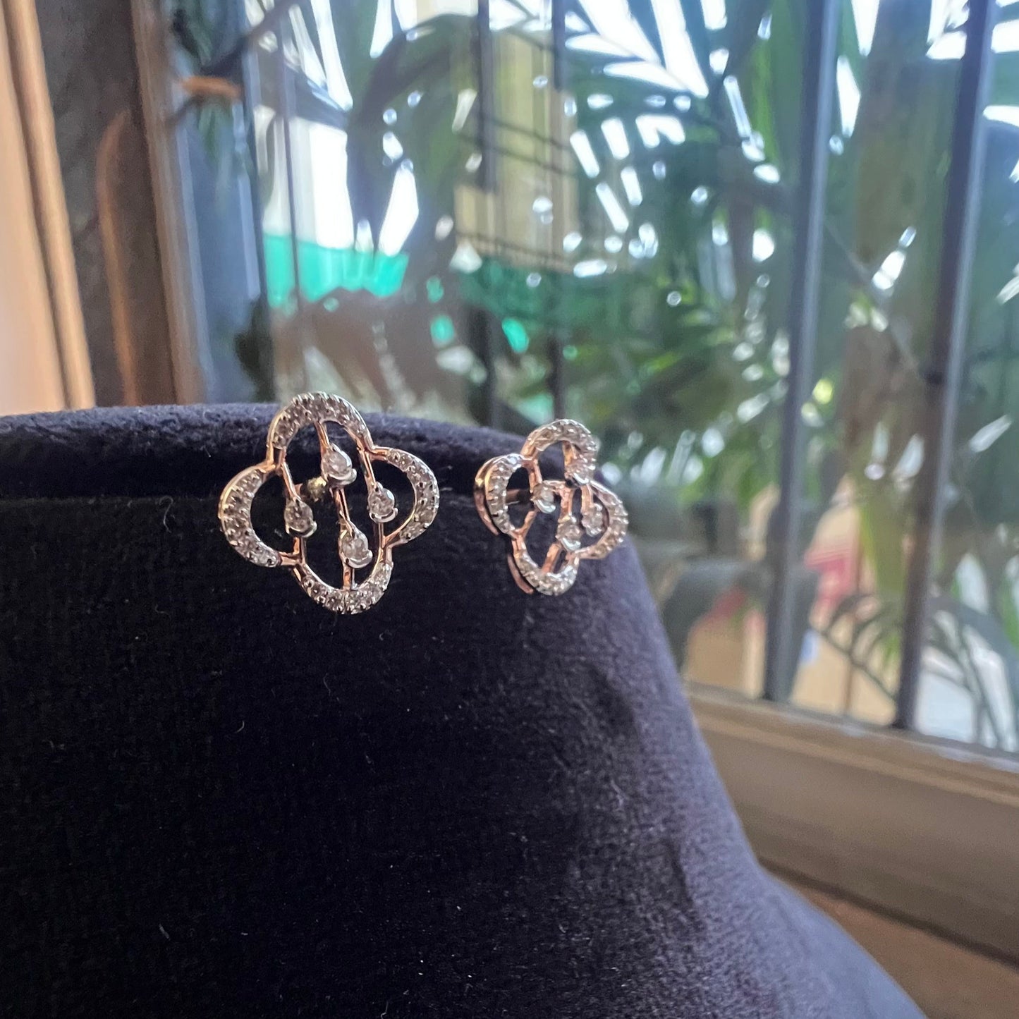 Pair of clover bloom diamond stud earrings in gold, designed with open quatrefoil petals and diamond accents.