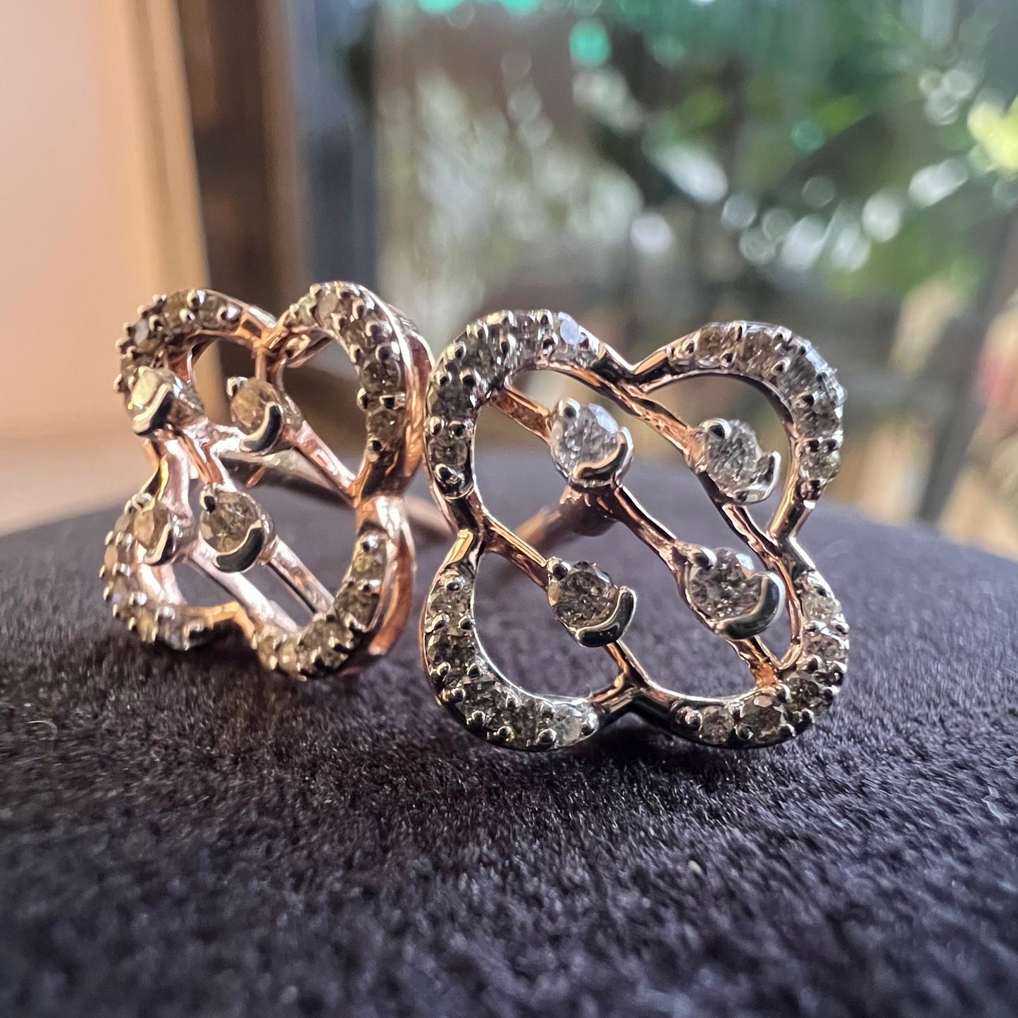 Close-up view of clover bloom diamond earrings in gold with openwork floral design and sparkling diamonds.