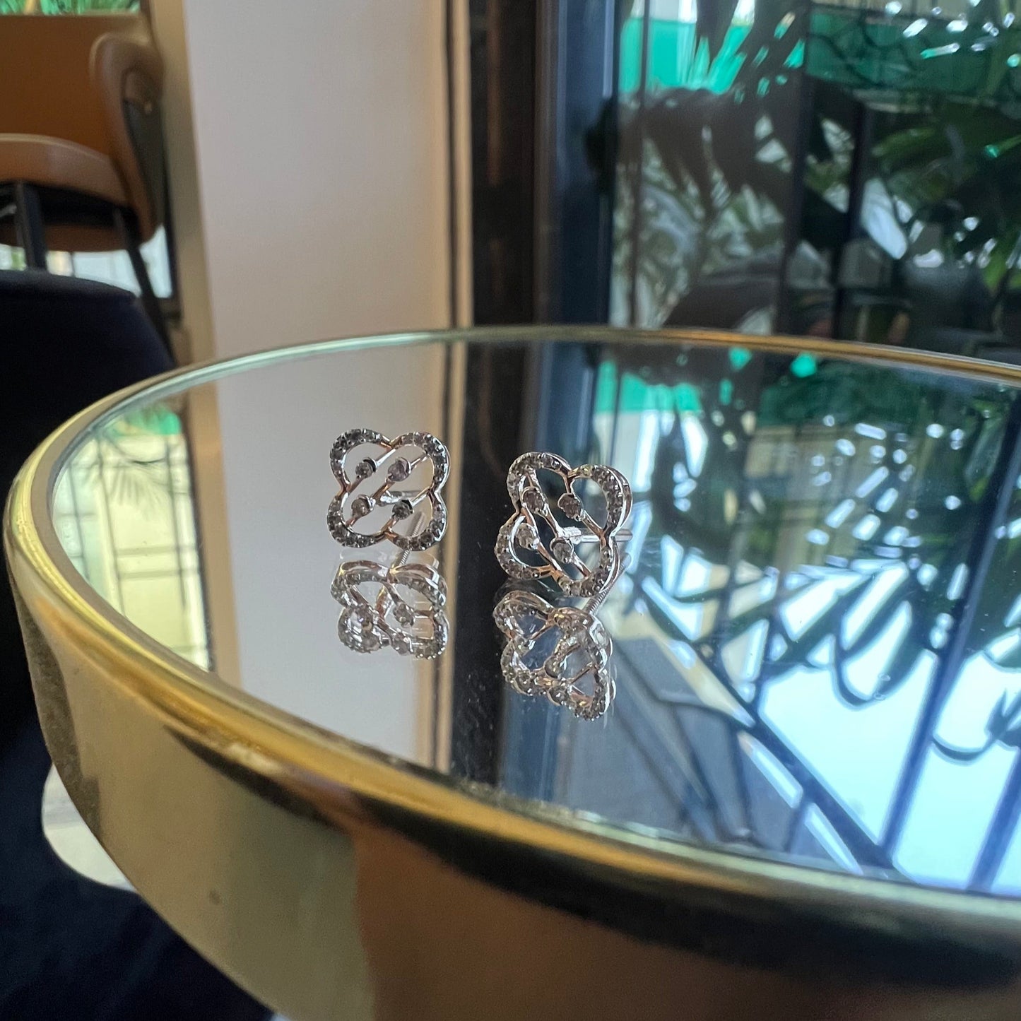 view of clover bloom diamond stud earrings in gold with openwork floral design and sparkling diamonds.