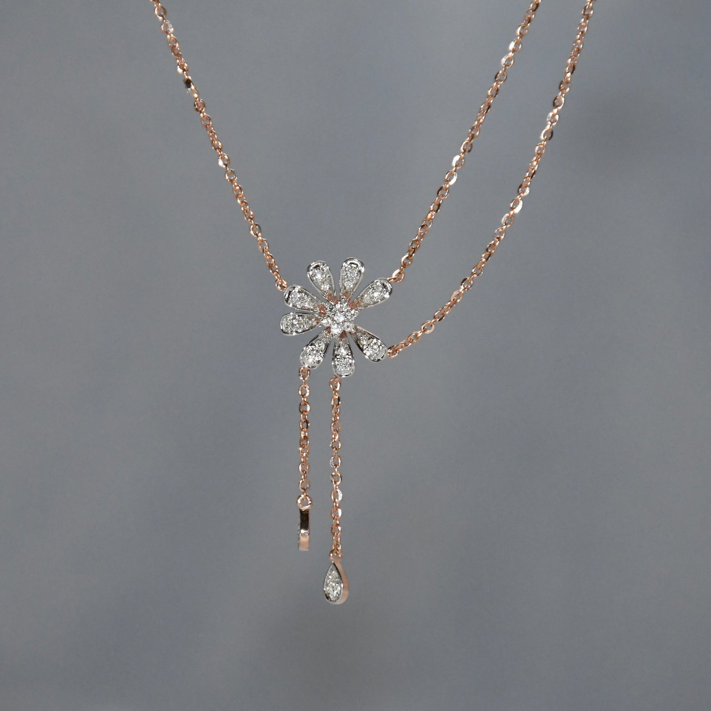 Rose gold necklace with a floral pendant on a gray background