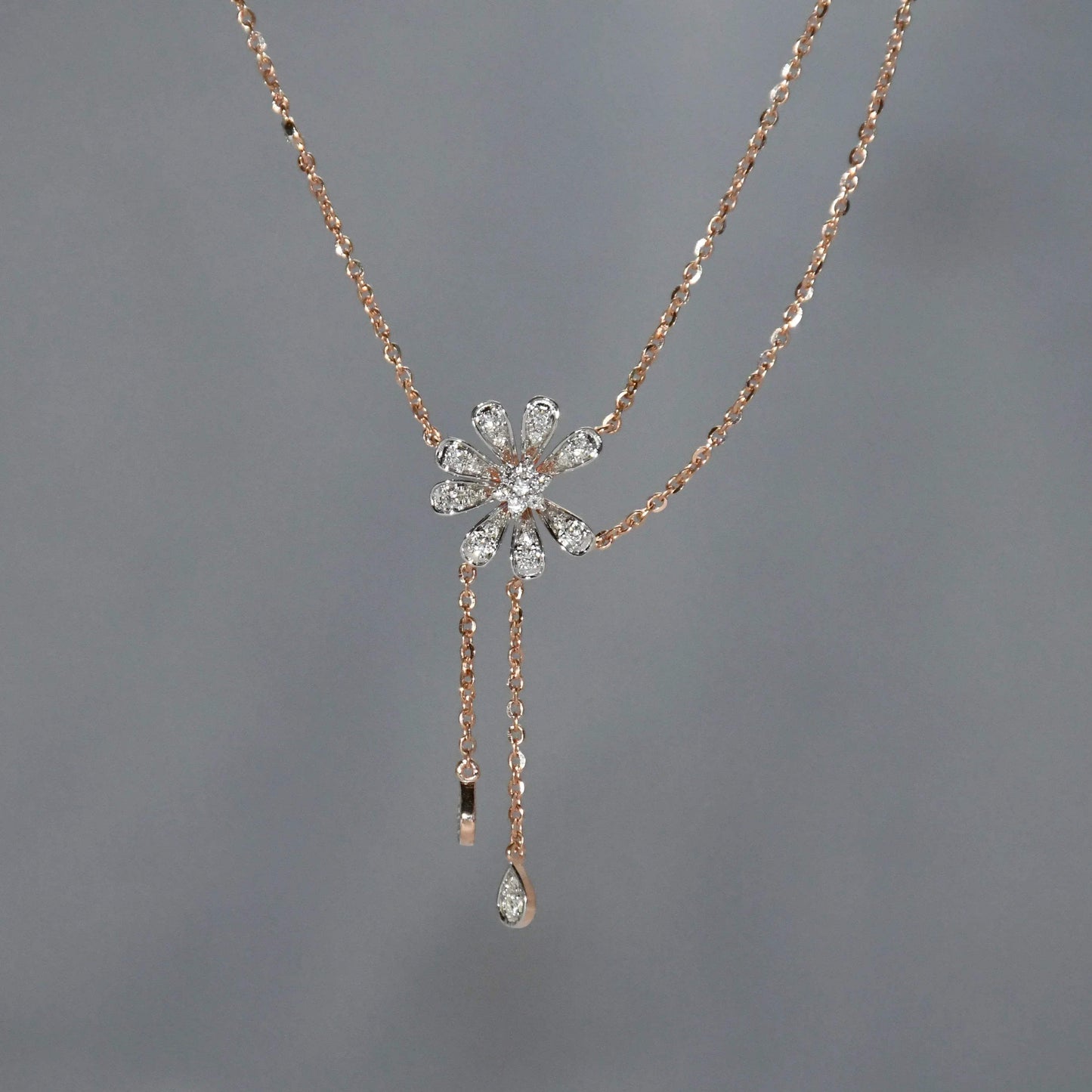 Rose gold necklace with a floral pendant on a gray background