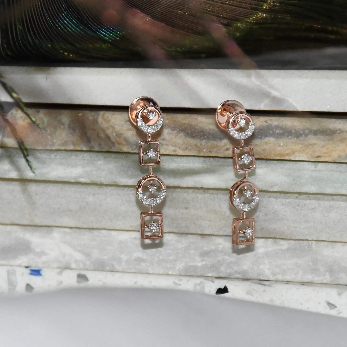 Rose gold earrings with clear diamonds on a marble surface