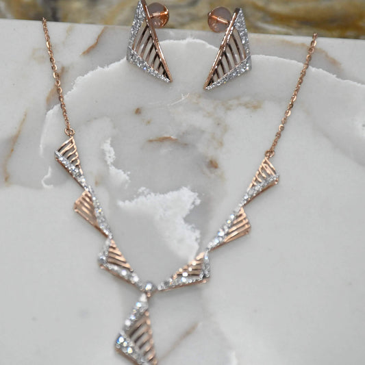 Gold diamond necklace and earrings on a marble surface.