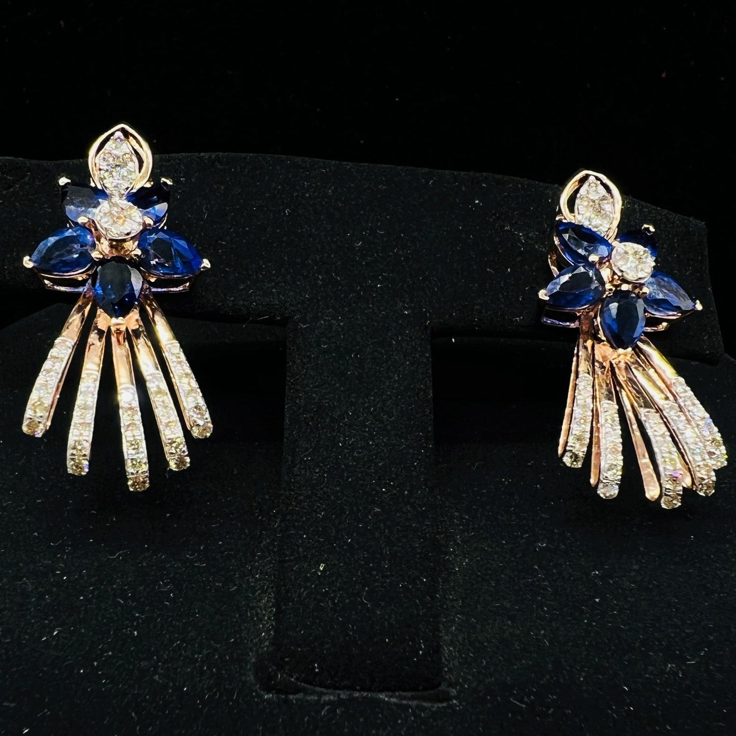 gold wedding earrings with round-cut blue color stones and clear diamonds displayed on a mannequin bust.