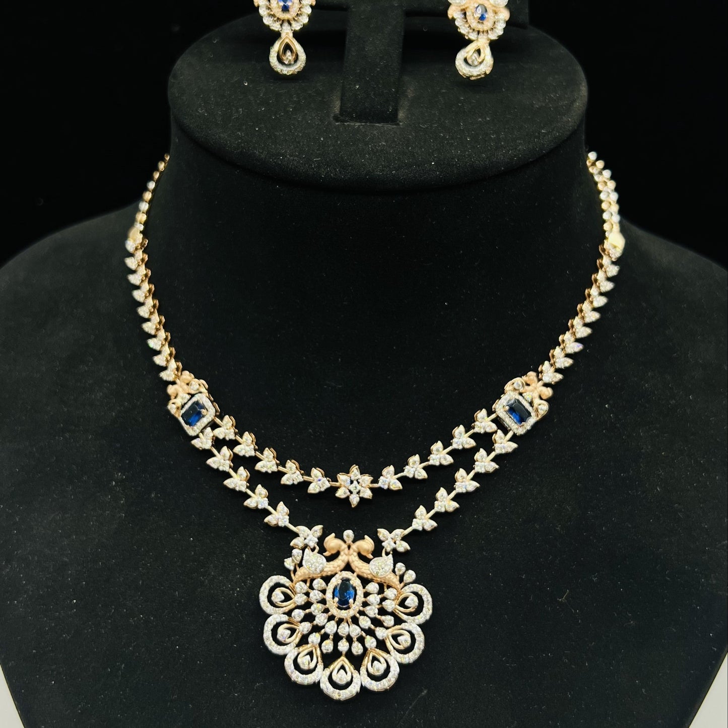 A gold diamond necklace with a floral pendant, displayed on a mannequin bust.