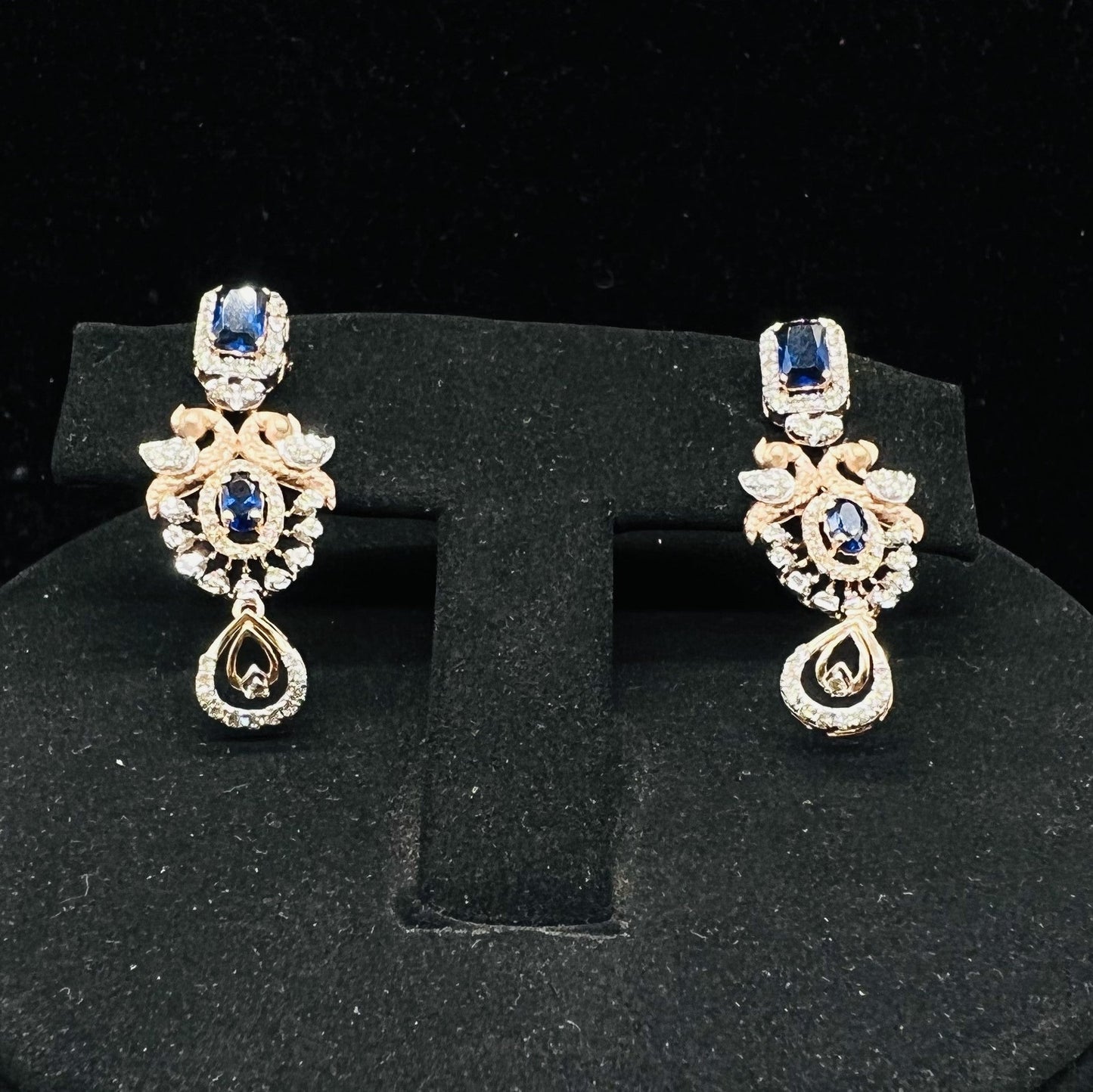 gold diamond earrings with a floral pendant, displayed on a mannequin bust.