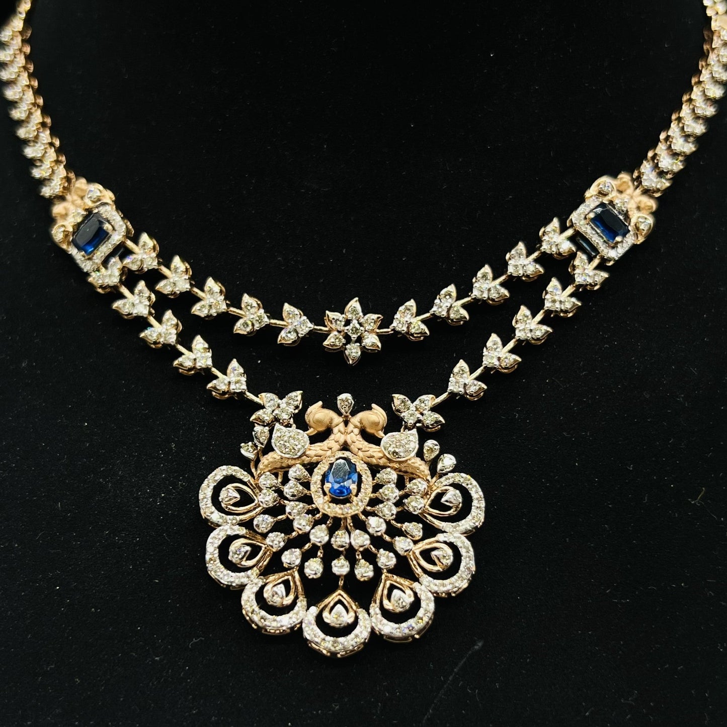 A gold diamond necklace with a floral pendant, displayed on a mannequin bust.