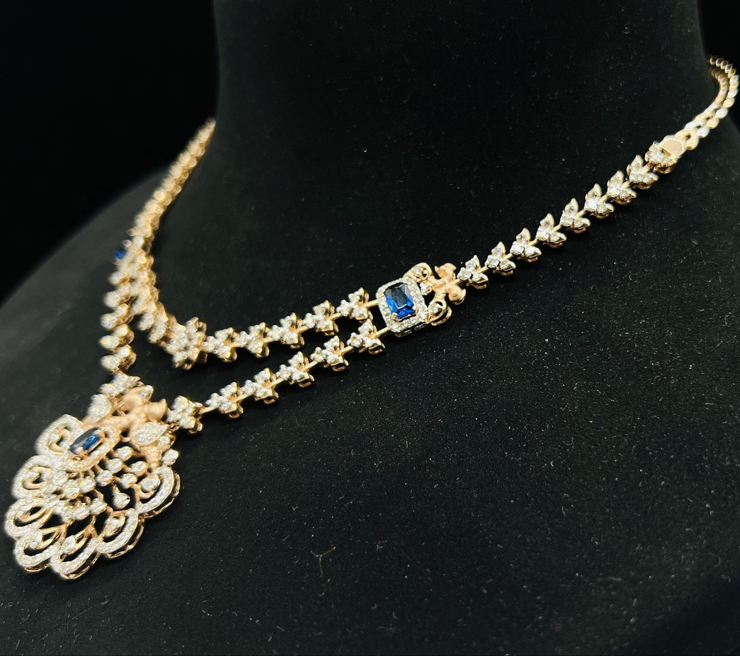 A gold diamond necklace with a floral pendant, displayed on a mannequin bust from left side.