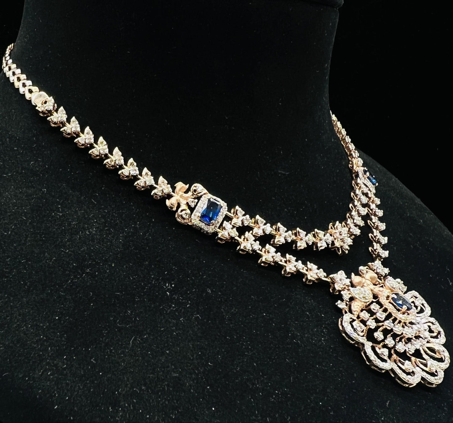 A gold diamond necklace with a floral pendant, displayed on a mannequin bust from right side.