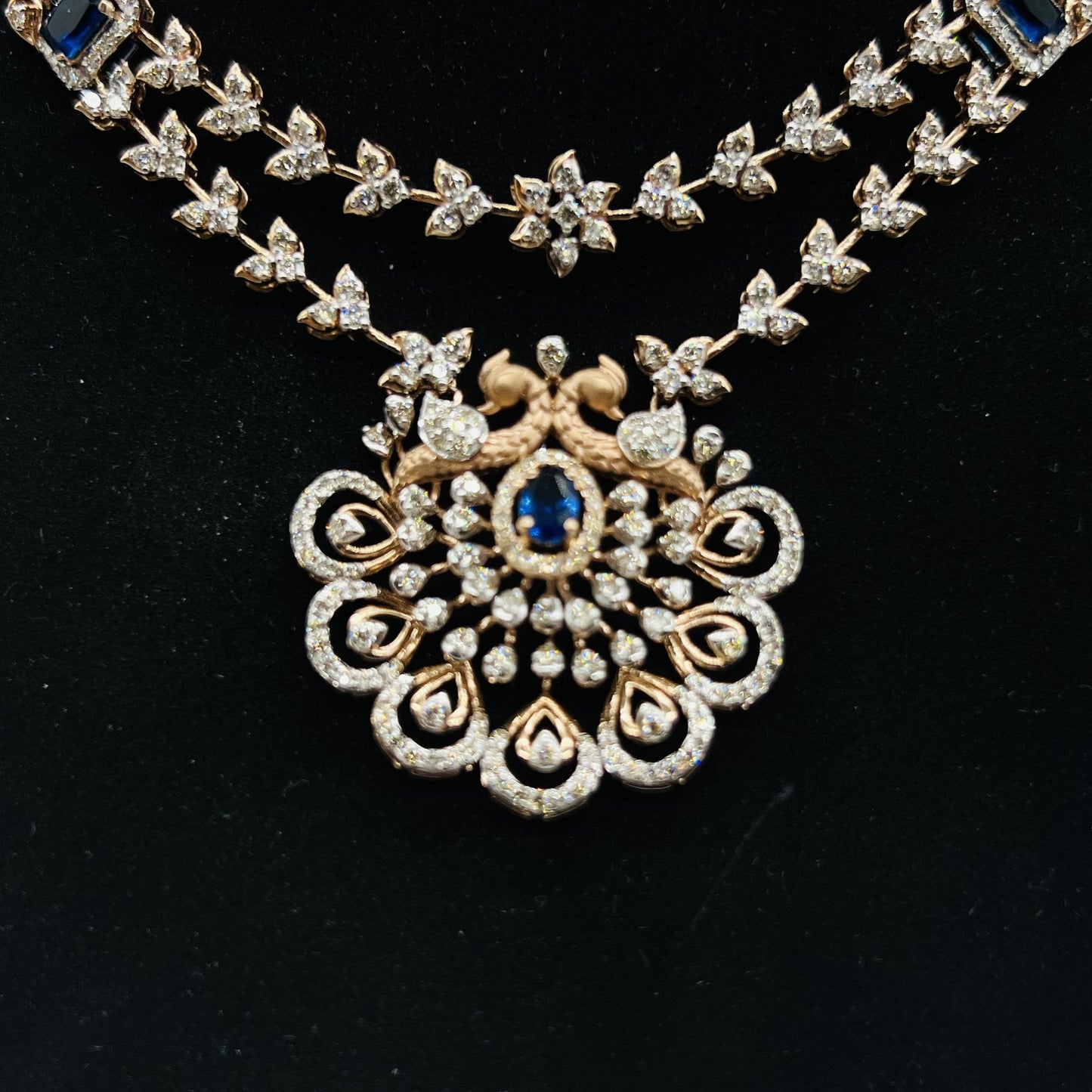 A gold diamond necklace with a floral pendant, displayed on a mannequin bust from front side.