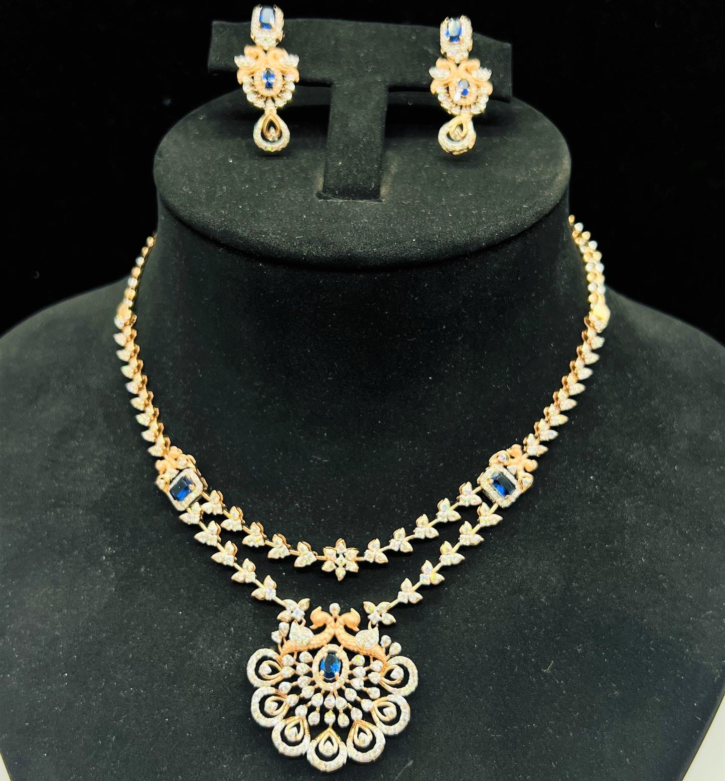 A gold diamond necklace with a floral pendant, displayed on a mannequin bust.