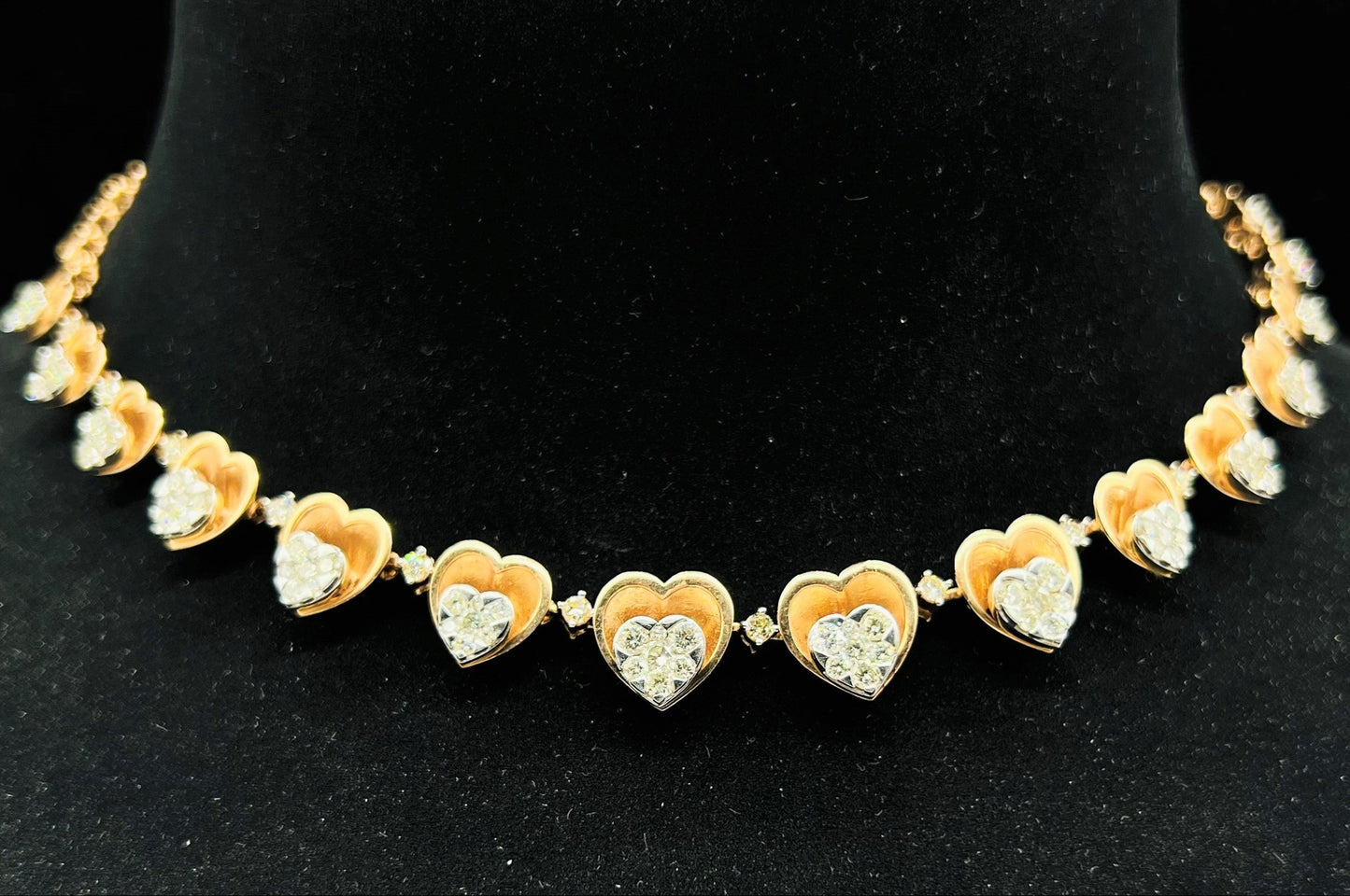 A gold necklace with round-cut diamond pendants, displayed on a black mannequin bust.