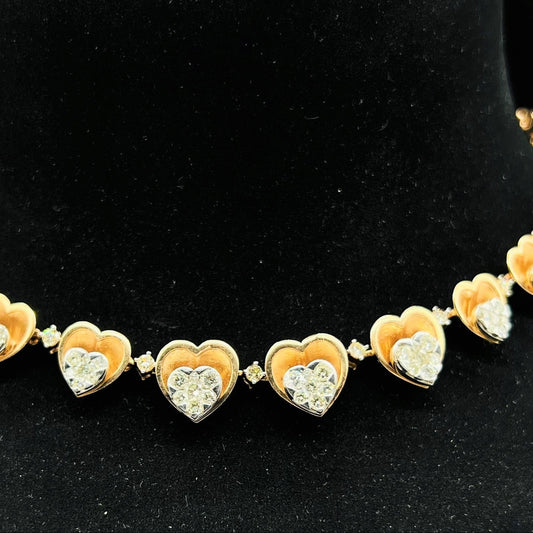 A gold necklace with round-cut diamond pendants, displayed on a black mannequin bust.